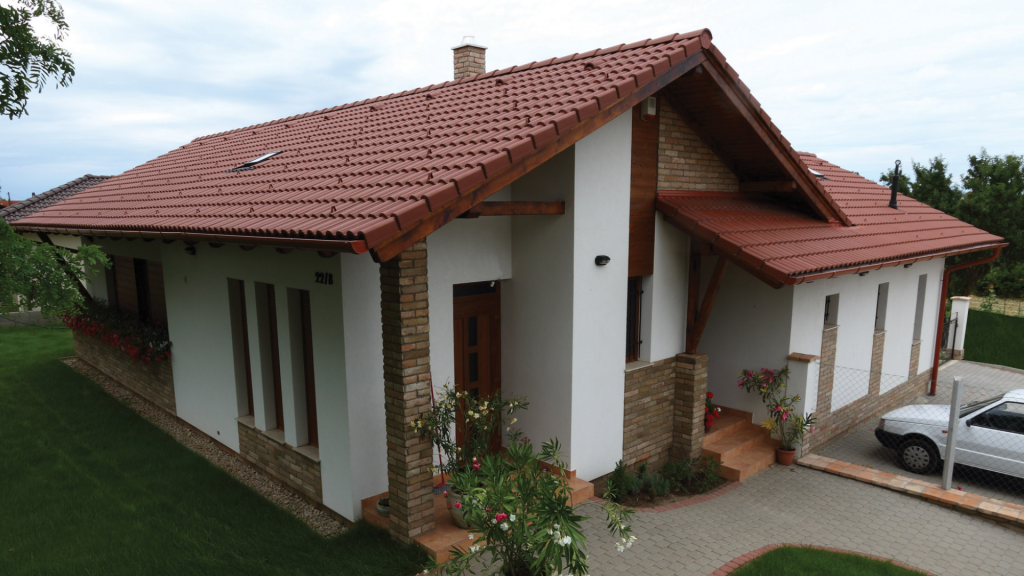 Danubia natúr színű, hullámos tetőcserép dísztéglával kombinált családi házon.